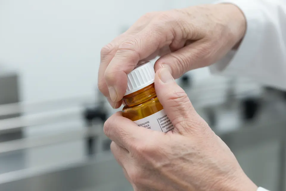 Hands twisting cap on amber medicine bottle